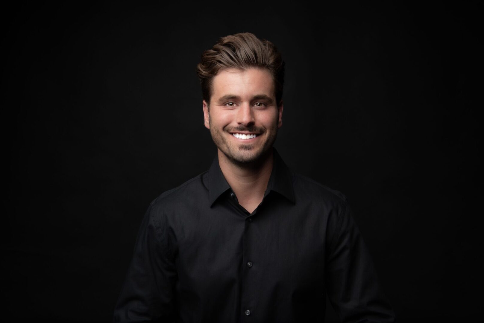 A man in black shirt smiling for the camera.