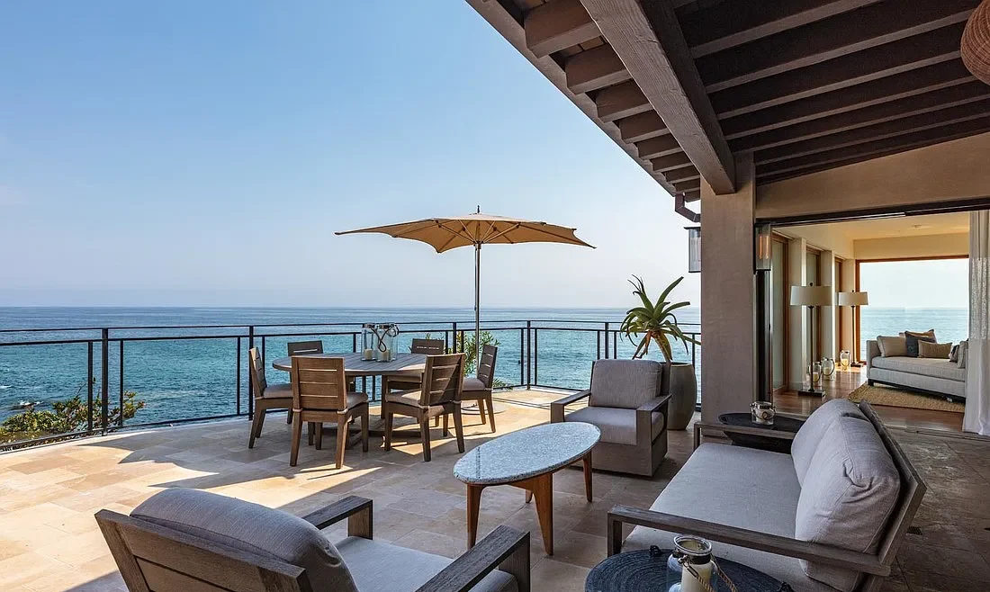 A patio with chairs and tables overlooking the ocean.